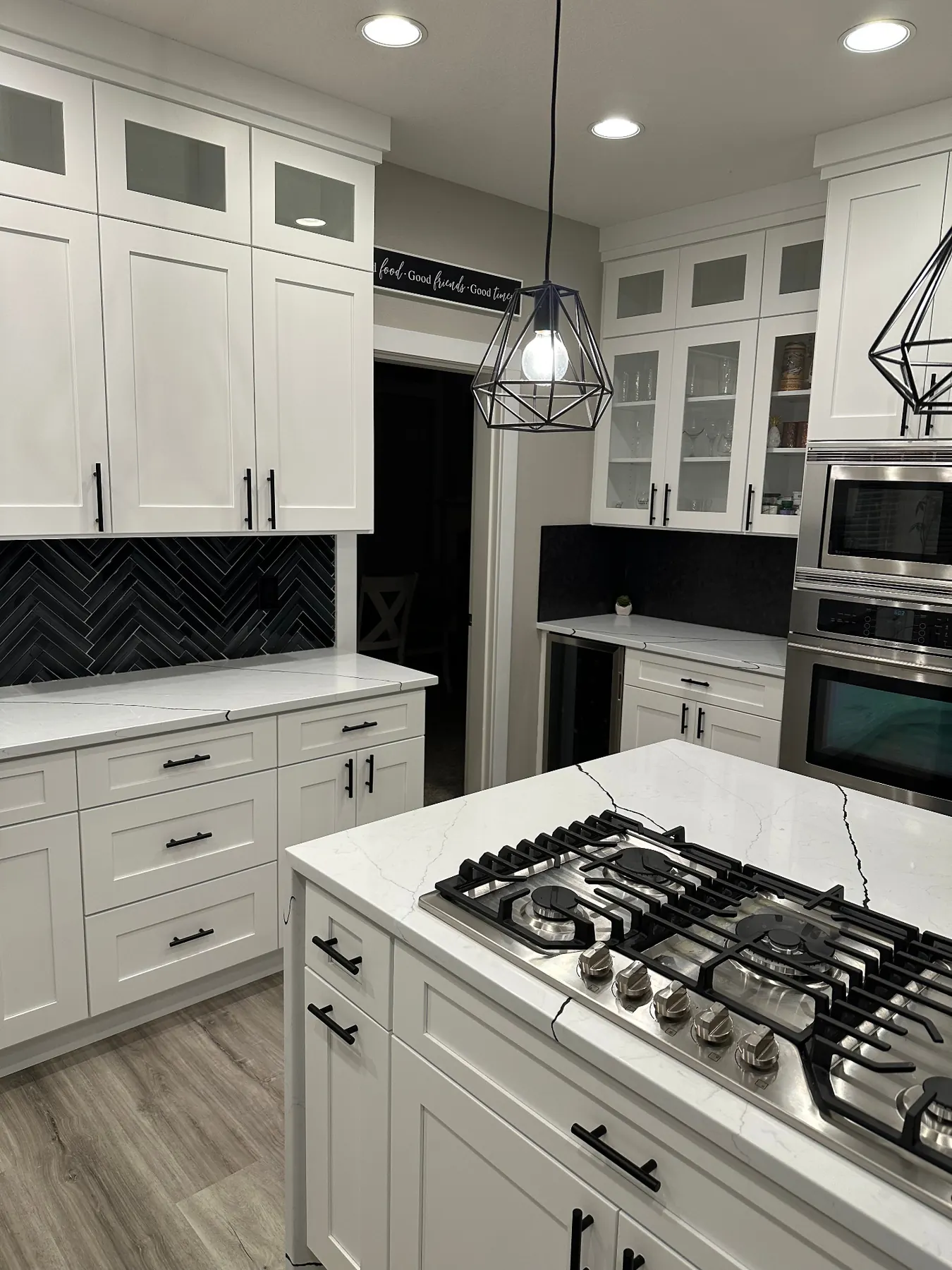 White shaker kitchen with black herringbone backsplash and quartz counters