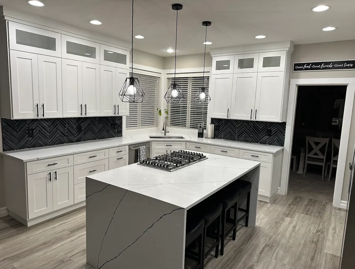 White shaker kitchen with black herringbone backsplash and quartz waterfall island